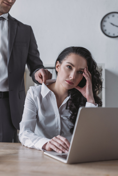 cropped view of businessman touching blouse of bored secretary sitting at workplace - Photo, Image