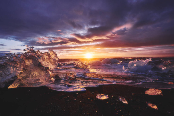 ジョクルサロン氷河ラグーンからの氷とダイヤモンドビーチでの日の出は岸に洗浄され、黒いビーチ、アイスランドのストランド - 写真・画像