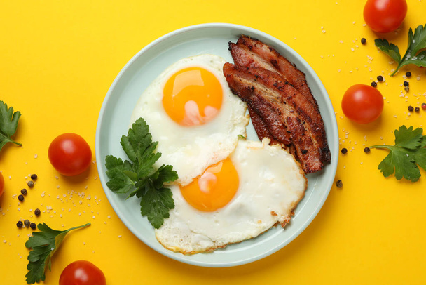 Delicious breakfast or lunch with fried eggs on yellow background, top view - Photo, Image
