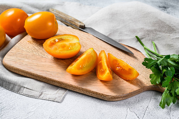 Cortado tomate cereza amarillo fresco en rodajas en una tabla de cortar. Fondo blanco. Vista superior. - Foto, imagen