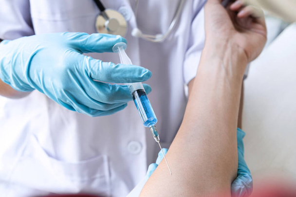 Γιατρός που κάνει τον εμβολιασμό με ένεση για την πρόληψη πανδημίας της νόσου, γρίπης ή ιού της γρίπης σε κλινική. - Φωτογραφία, εικόνα