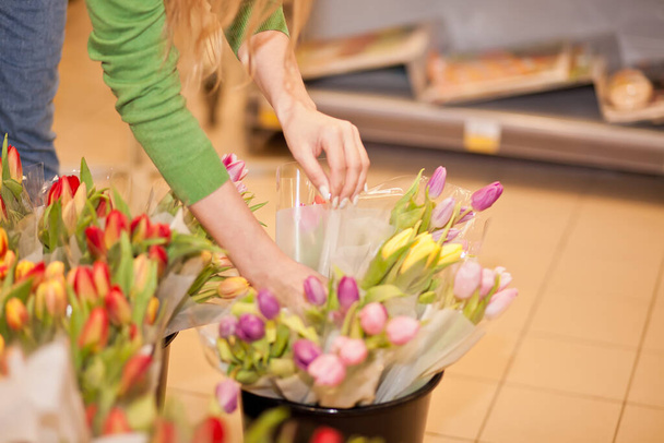 Young woman picks tulips in the store. - Zdjęcie, obraz