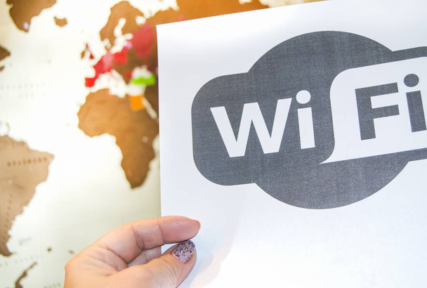 Wi-Fi-vyöhykkeen symboli naisen kädessä, yhteyspiste maailmankartan taustalla, moderni langaton viestintä, internet online-konseptiteknologia
. - Valokuva, kuva
