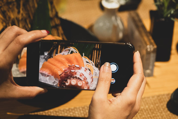 Руки, які роблять фото сашімі японської їжі зі смартфоном
 - Фото, зображення