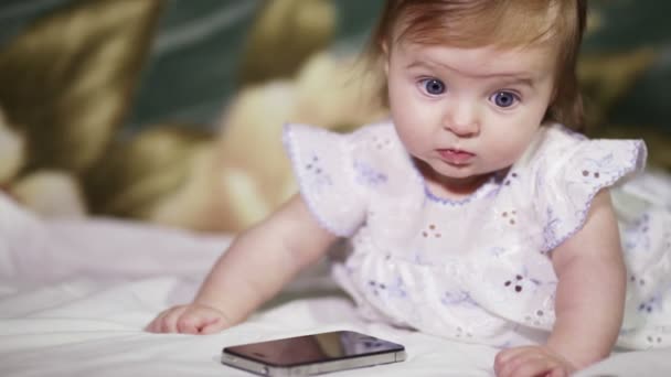 Infant girl listening to a mobile phone - Filmmaterial, Video