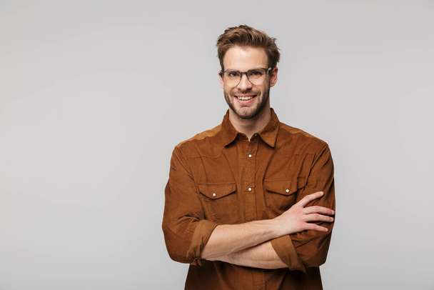 Portrait of cheerful young man in eyeglasses posing at camera and smiling isolated over white background - Foto, Imagen