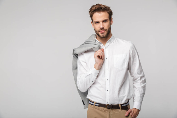 Portrait of confident young man wearing shirt posing on camera with jacket isolated over white background - Zdjęcie, obraz