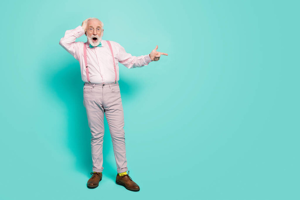 Full length photo of funny grandpa indicate fingers empty space offer black friday prices open mouth wear pink shirt suspenders bow tie pants boots socks isolated teal color background - Foto, afbeelding