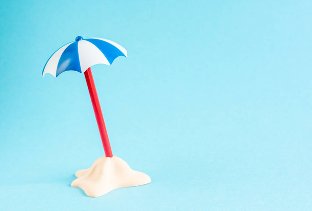 Malý písečný ostrůvek s deštníkem na pastelově modrém pozadí. Minimální letní koncept. Plocha - Fotografie, Obrázek