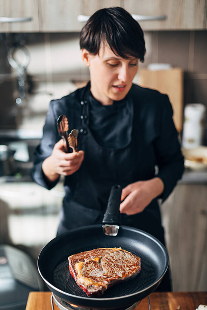 Chef frying ribeye steak in a pan - Fotoğraf, Görsel
