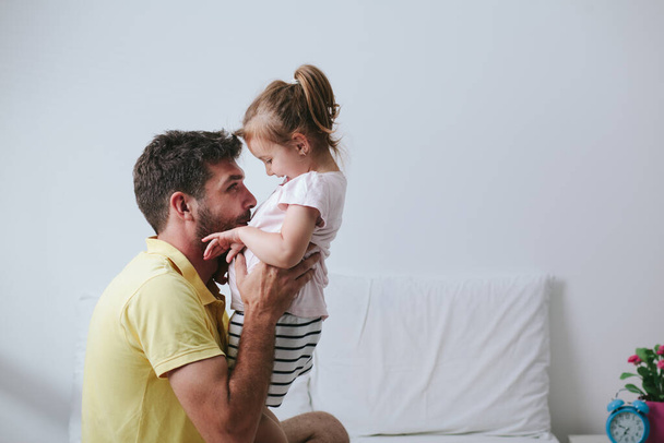 Father and daughter playing on bed - 写真・画像