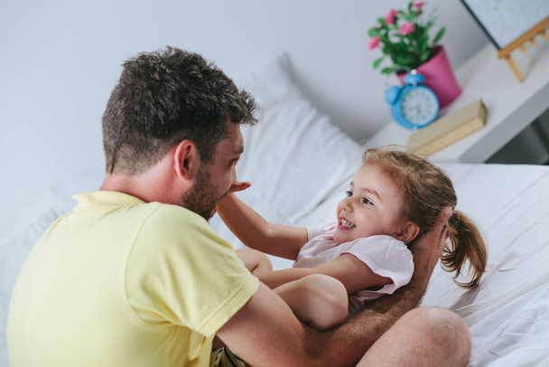 Father and daughter playing on bed - Foto, Imagen