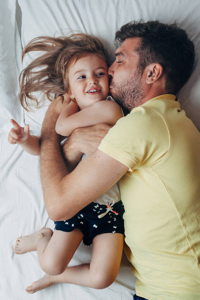 Father and daughter playing on bed - Фото, изображение