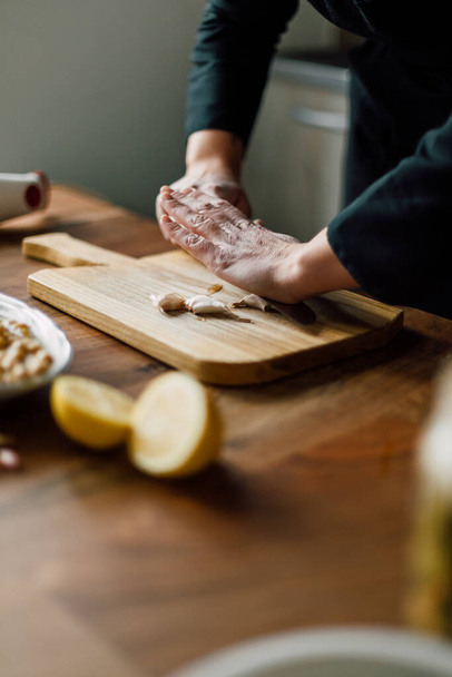 Chef crushing garlic with knife on a wooden board - Φωτογραφία, εικόνα