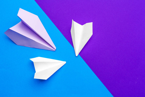 white paper airplane on a blue and purple paper background - Fotoğraf, Görsel