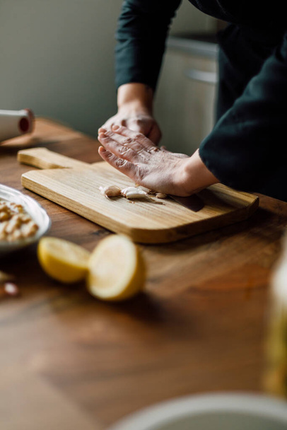 Chef crushing garlic with knife on a wooden board - Photo, image