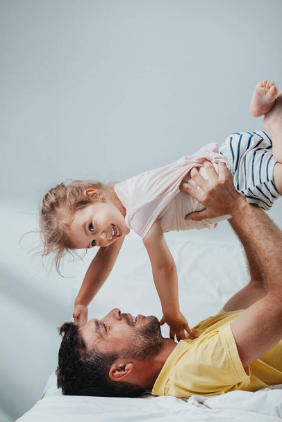 Father and daughter playing on bed - Foto, afbeelding