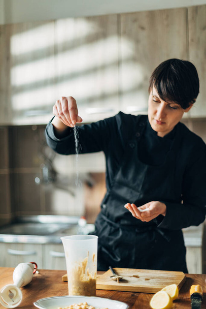 Chef putting salt in a plastic bowl - Photo, image