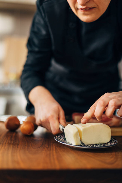 Chef cutting butter on a wooden board - Фото, зображення