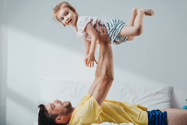Father and daughter playing on bed - Fotó, kép