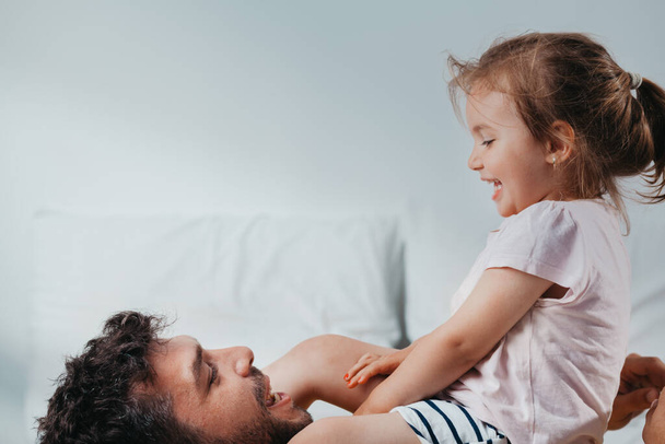 Father and daughter playing on bed - Φωτογραφία, εικόνα