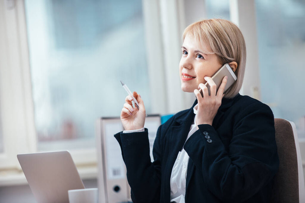 Young woman talking on a cellphone in her office - Foto, Imagen