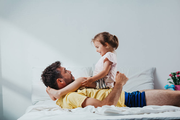 Father and daughter playing on bed - Foto, imagen