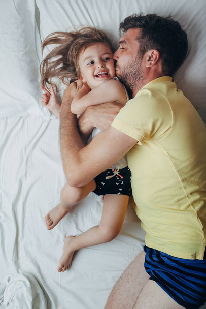 Father and daughter playing on bed - Photo, Image