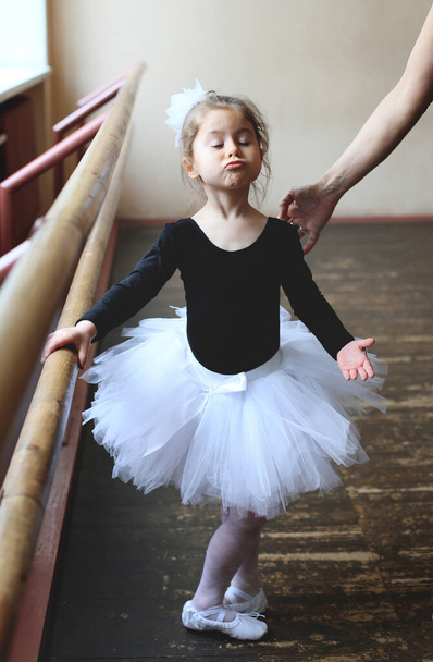 a tanár segít a kis vicces balerinának helyesen előadni a balettet pas - Fotó, kép