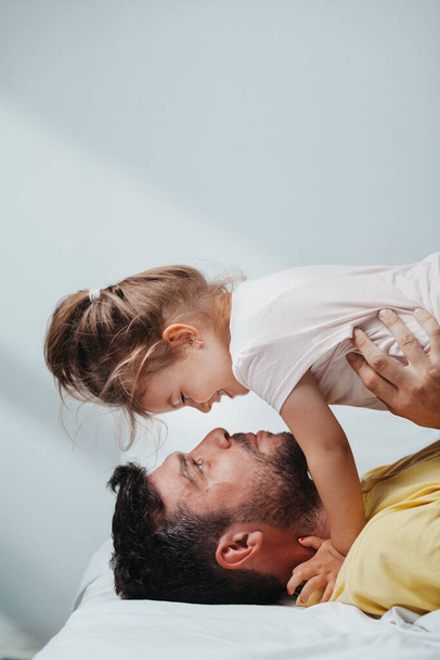 Father and daughter playing on bed - Photo, image