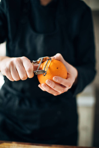 Chef peeling orange in the kitchen - Photo, image