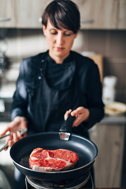 Chef frying ribeye steak in a pan - Fotó, kép