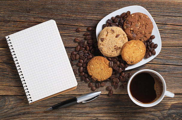Tasse Kaffee, Notizbuch und Kekse auf Holztisch, Draufsicht - Foto, Bild