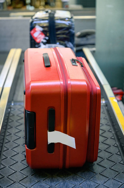 Equipaje rojo en la cinta transportadora para comprobar y escanear en el mostrador de facturación en el aeropuerto
 - Foto, Imagen