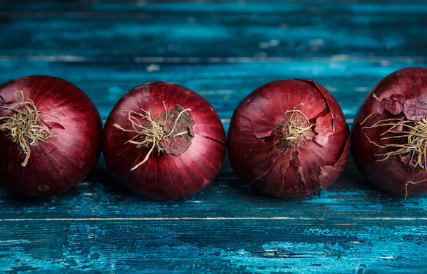 Red onions on a blue background - 写真・画像