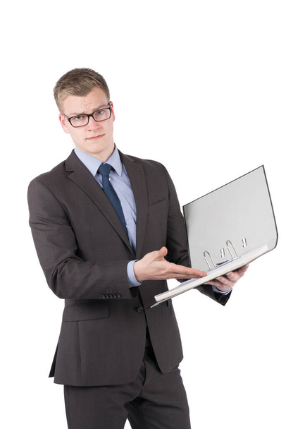 A photograph of a young,dissatisfied businessman with glasses pointing his hand into an open file order. The man looks at the camera. - Фото, изображение