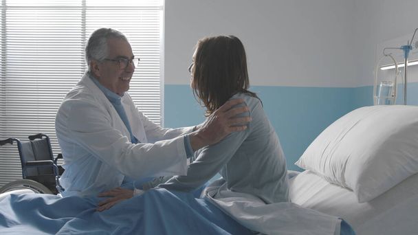 Caring doctor cheering up a young patient lying in a hospital bed - Foto, immagini