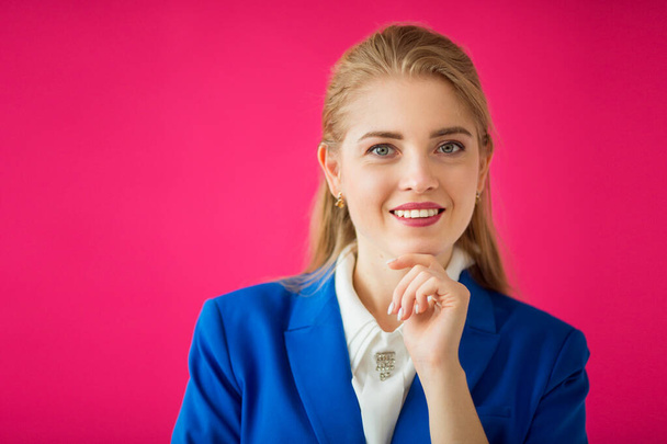 beautiful young woman in a blue jacket on a pink background - Фото, зображення