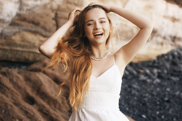 Gorgeous girl in a long white dress on the ocean at the beach. The model is inherited by nature laughing, having fun, going crazy. Happy girl on vacation, summer, emotions. The bride on vacation. - Photo, Image
