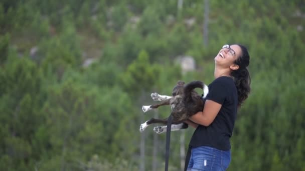 Γυναίκα διασκεδάζει παίζοντας με ένα σκυλί σε αργή κίνηση στην αγκαλιά της σε ένα άγριο τοπίο παραλία στο εθνικό πάρκο Geres, Πορτογαλία - Πλάνα, βίντεο