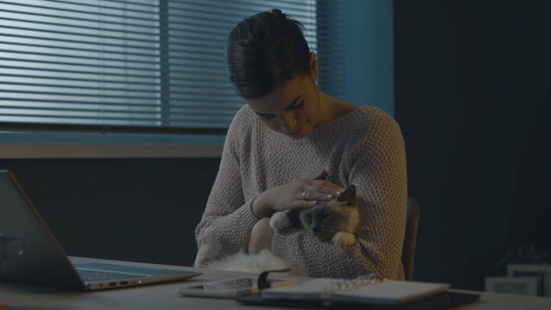 Woman sitting at desk and holding her beautiful cat, pet lifestyle concept - Φωτογραφία, εικόνα