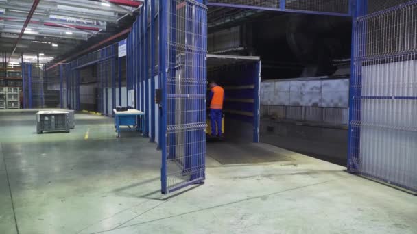 Worker on loader transports boxes in warehous. Scene. Worker standing on loader controls it to transport cargo boxes in factory warehouse - Footage, Video