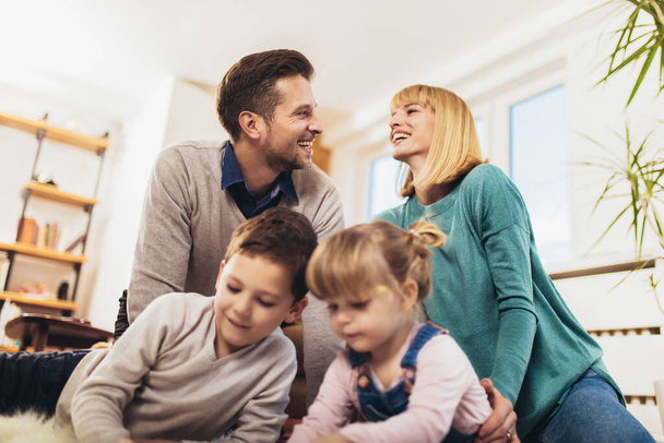 Glückliche Familie, die sich auf dem Fußboden oder im Wohnzimmer zu Hause amüsiert und lacht. Selektiver Fokus. - Foto, Bild