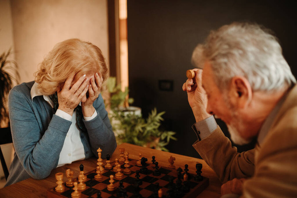 Retrato de mujer rubia con la cara en la mano porque hizo mal movimiento en el juego de ajedrez contra su marido
. - Foto, Imagen