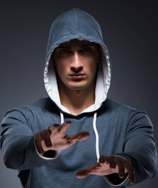 Jeune homme portant un sweat à capuche appuyant sur des boutons virtuels - Photo, image