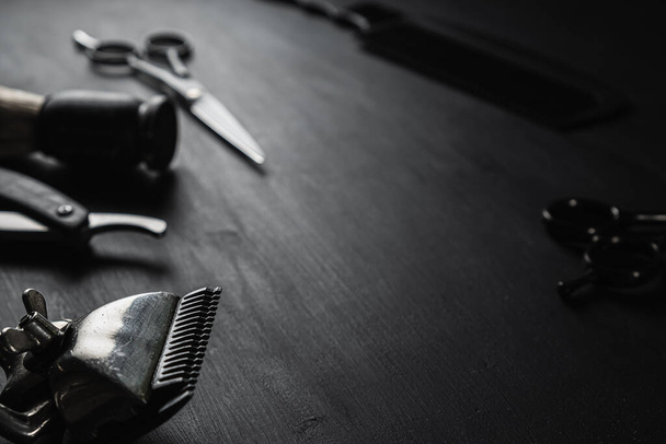 Na czarnej, zakurzonej powierzchni są stare narzędzia fryzjerskie. Vintage ręczny strzyżenie grzebień maszynka do golenia szczotka szczotka do golenia nożyczki fryzjerskie. Czarny monochromatyczny. poziomy. - Zdjęcie, obraz