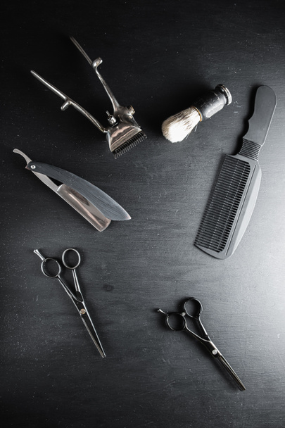 Siyah tozlu bir yüzeyde eski berber aletleri vardır. Klasik manuel saç kesme makinesi tıraş fırçası tıraş fırçası tıraş fırçası saç kesme makası. siyah monokrom. Dikey. Üst Manzara. düz yat. - Fotoğraf, Görsel