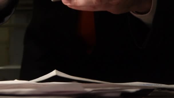 Un homme en costume déplace des feuilles de papier sur la table, regarde et photographie. Le texte sur papier est flou
. - Séquence, vidéo