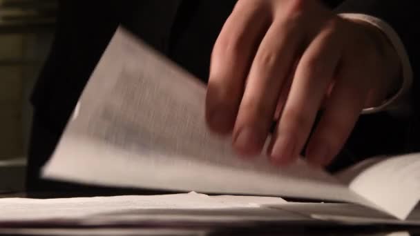 Een man in een pak schuift vellen papier op tafel, kijkt en fotografeert. Tekst op papier is niet scherp.. - Video