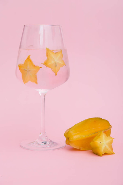 Copa de cóctel helado fresco decorado con rodaja de fruta de la estrella sobre fondo rosa. Disparo vertical
. - Foto, imagen